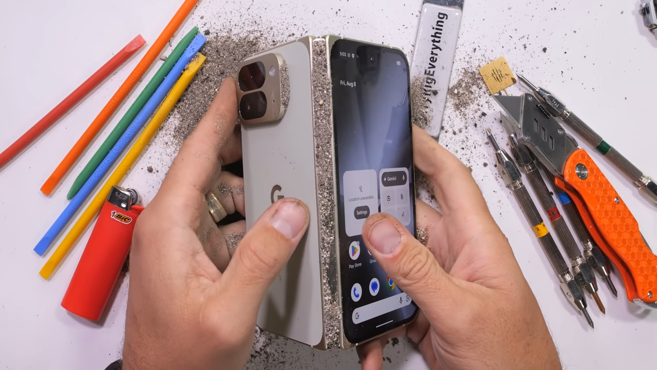 Le Pixel 10 Pro Fold pendant le test de résistance, avec du sable introduit dans la charnière pour vérifier la protection IP68.